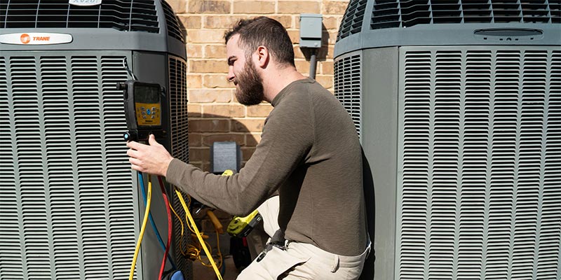 Service technician conducting inspection on air conditioning unit